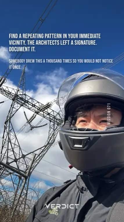 Verdict mission 71, "Find a repeating pattern in your immediate vicinity. The architects left a signature. Document it.", answered with a helmet selfie beneath a transmission pylon.